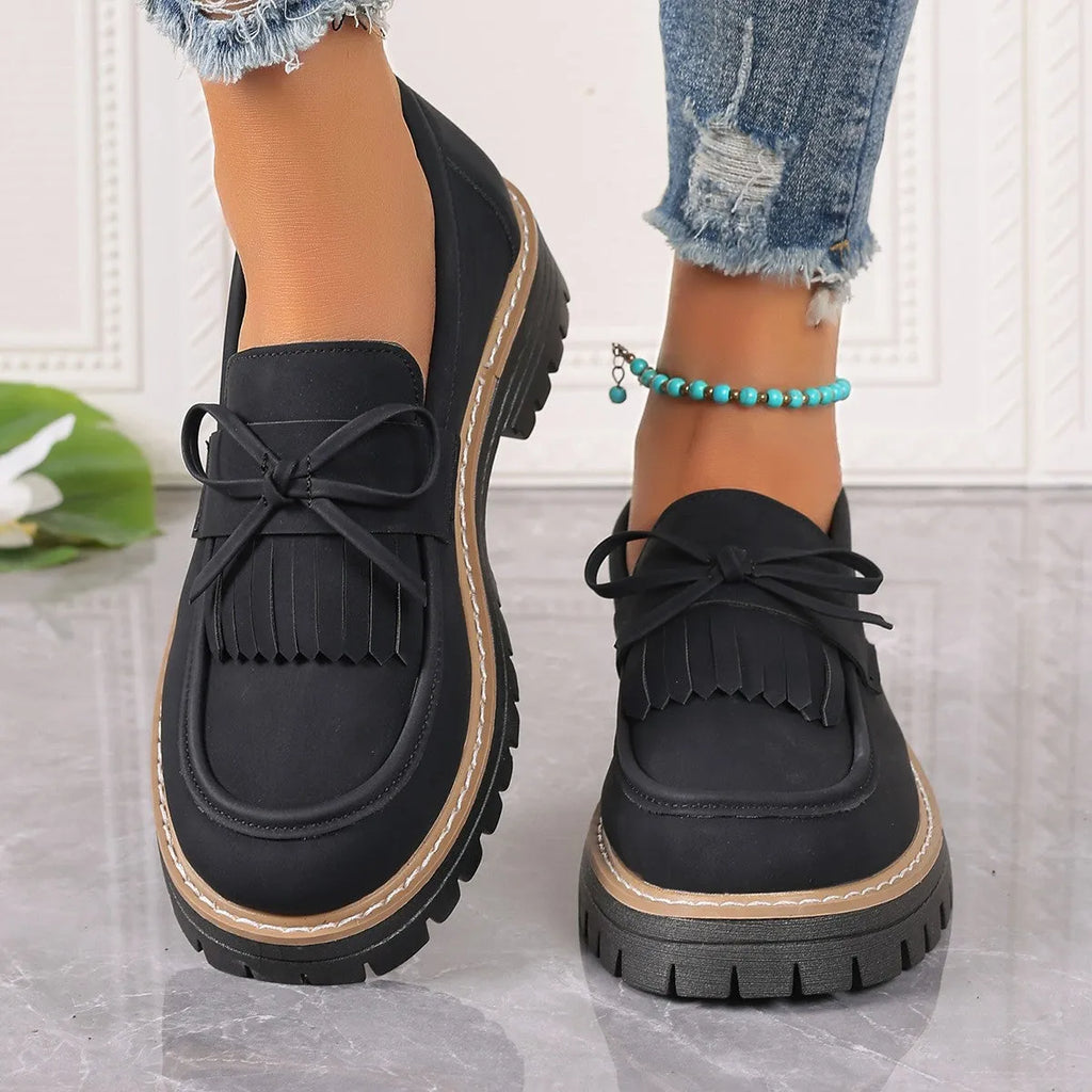 Black women's loafers with a tassel and bowknot decoration on the front, showing a round toe and low-top design.