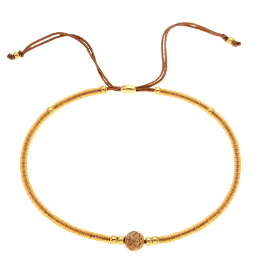 Close-up of a woman's handmade Bohemian bracelet with colourful geometric glass and glaze beads.