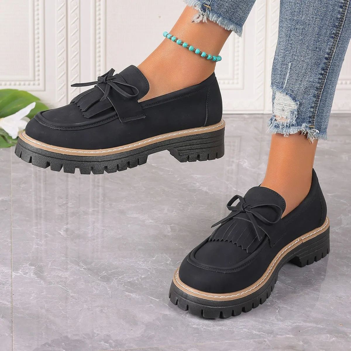 Black women's loafers with a tassel and bowknot decoration on the front, showing a round toe and low-top design.