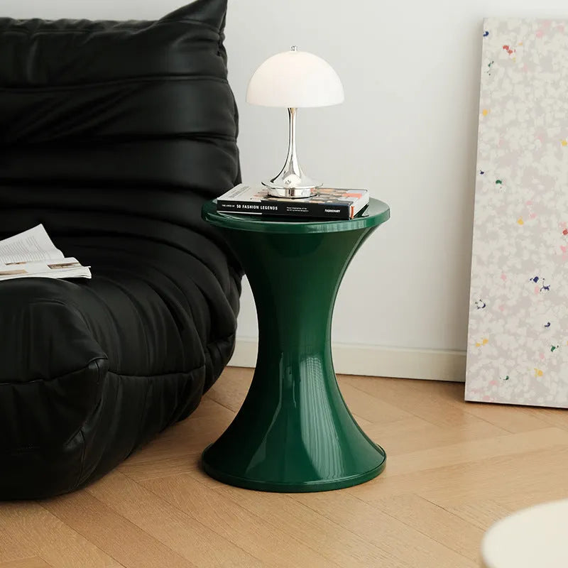A white hourglass-shaped plastic shoe changing stool on a wooden floor.
