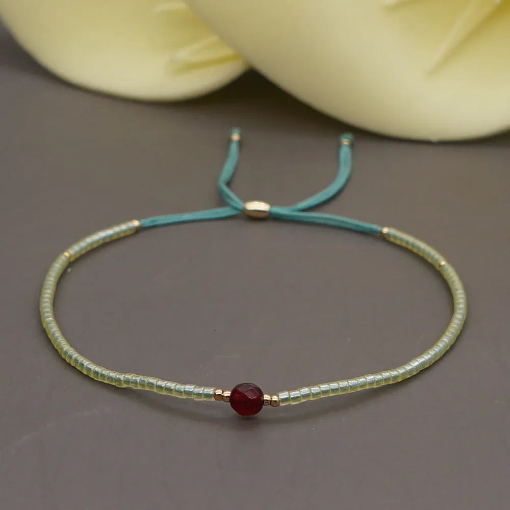 Close-up of a woman's handmade Bohemian bracelet with colourful geometric glass and glaze beads.