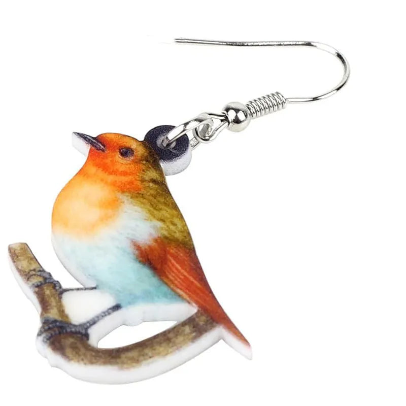 Close-up of blue titmouse and geometric zodiac pendant earrings made from printed acrylic.