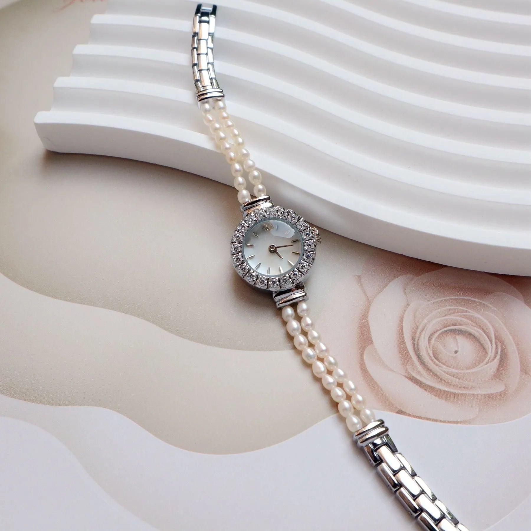 Light gold women's bracelet watch with freshwater pearls, an 18mm round dial, and a stainless steel folding buckle.