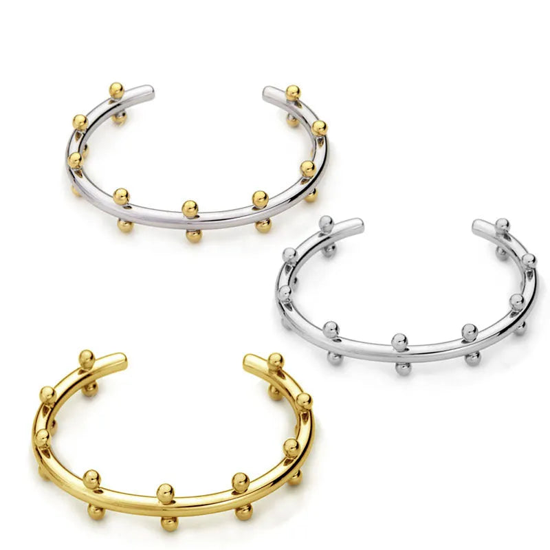 Stainless steel C-shaped bean beads with textured rivet design in gold, steel, and steel gold colours next to an alloy bracelet.