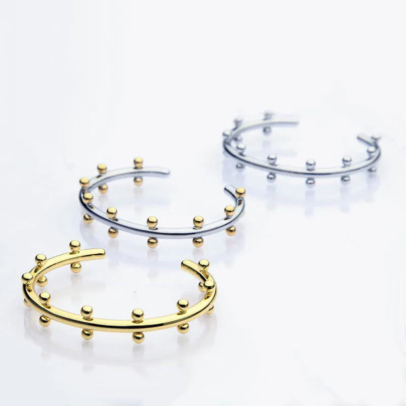 Stainless steel C-shaped bean beads with textured rivet design in gold, steel, and steel gold colours next to an alloy bracelet.
