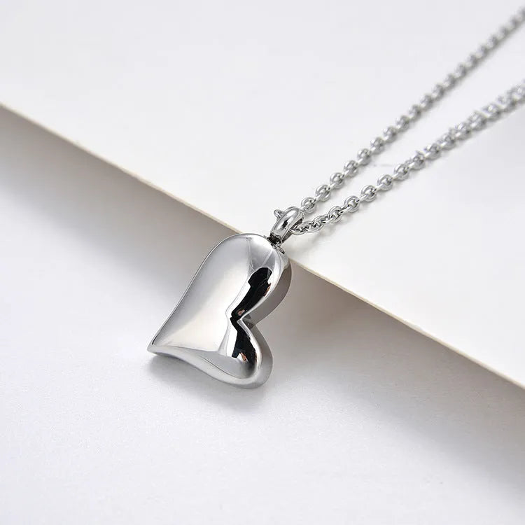 Silver curved peach heart stainless steel pendant necklace on display