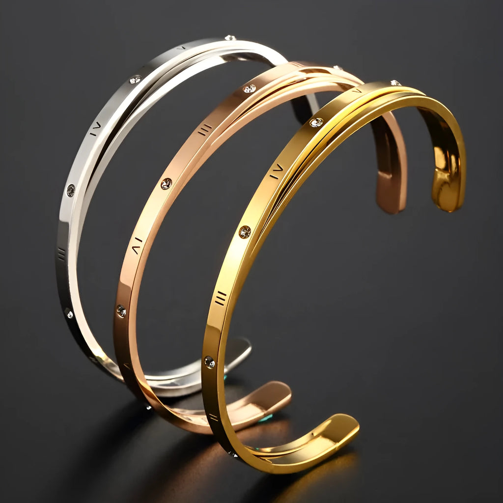 Open-ended stainless steel bracelet with inlaid zircon stones and a love charm in rose gold colour.