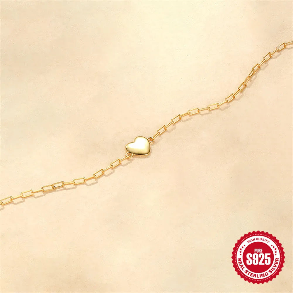 Close-up of a women's sterling silver bracelet with a glossy heart charm on an adjustable clip chain.