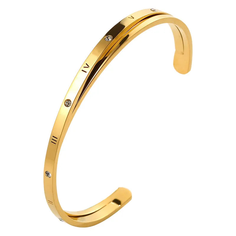 Open-ended stainless steel bracelet with inlaid zircon stones and a love charm in rose gold colour.