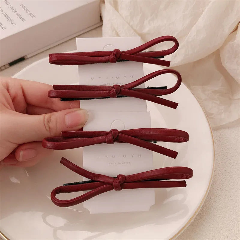 Wine red leather bow hair barrette on a white background.
