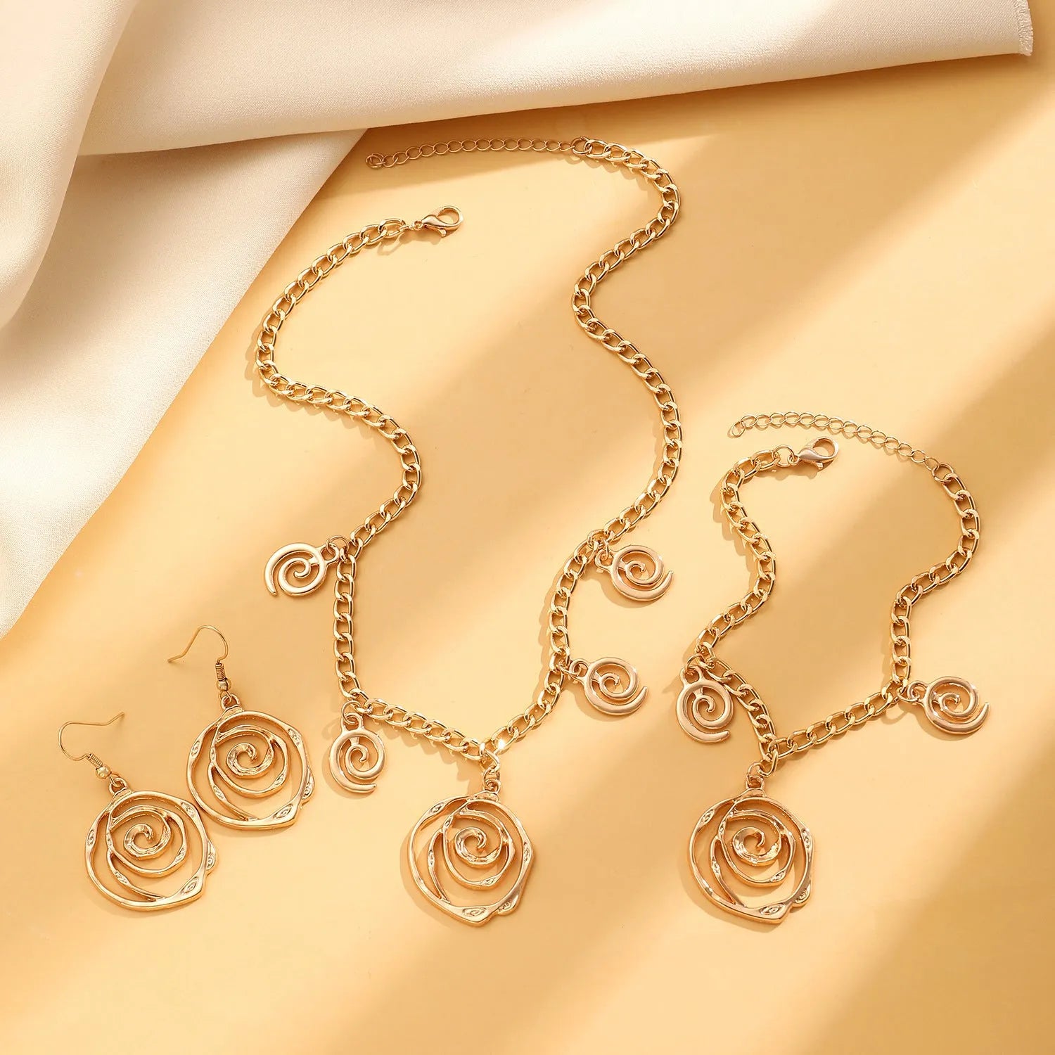 Spiral donut jewellery set showing necklace, bracelet, and ear hooks in gold or silver tone alloy