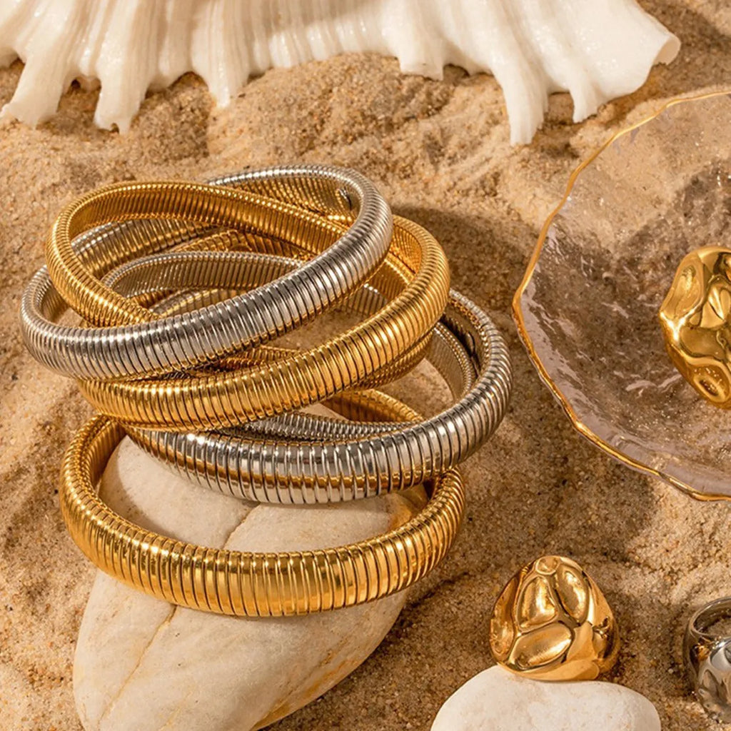 Gold women's elastic bracelet with a wide vertical stripe pattern, shown on a wrist.