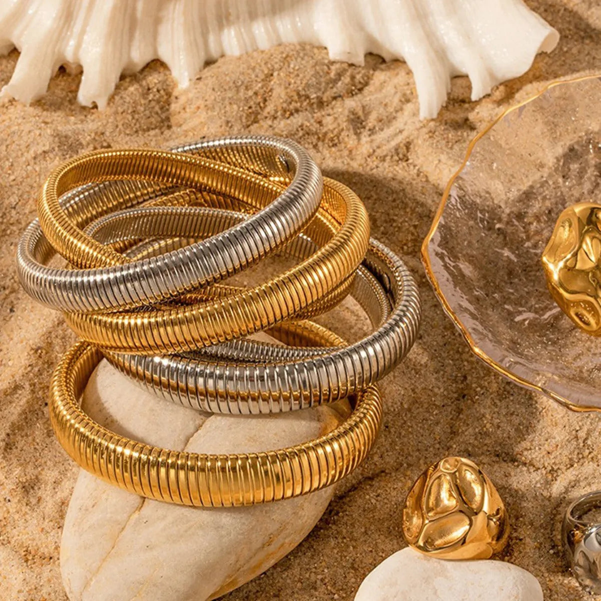 Gold women's elastic bracelet with a wide vertical stripe pattern, shown on a wrist.