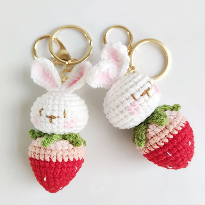 Close-up of a white hand-woven wire rabbit keychain pendant with a strawberry pattern detail.