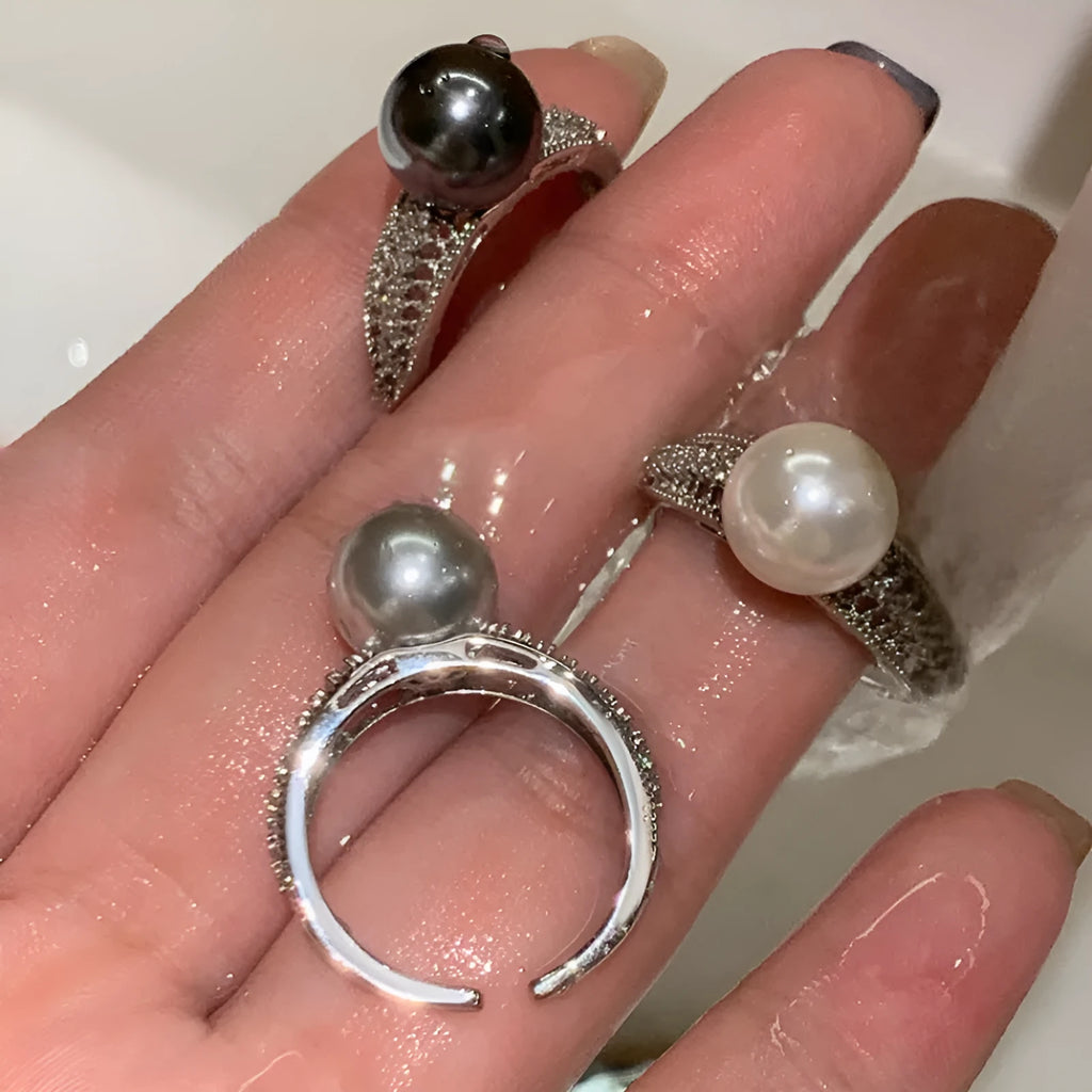 Women's adjustable copper ring with black pearl and geometric open design on an index finger.