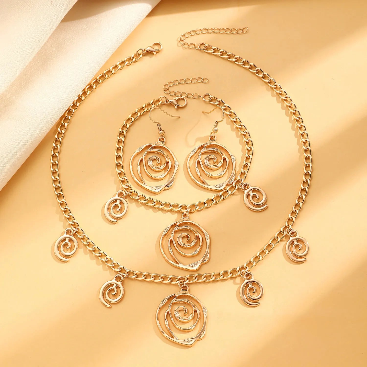 Spiral donut jewellery set showing necklace, bracelet, and ear hooks in gold or silver tone alloy