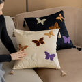 Square beige cushion with embroidered Chinese-style butterfly design.