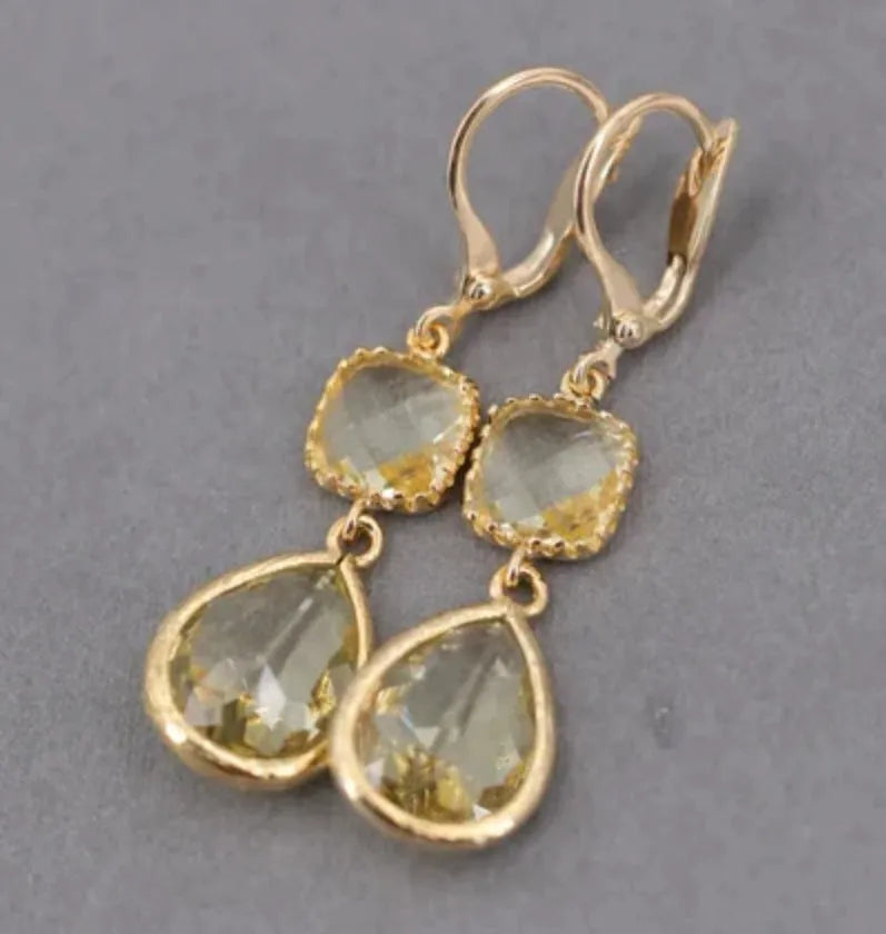 Gold geometric fringe earrings with water droplet design elements on white background