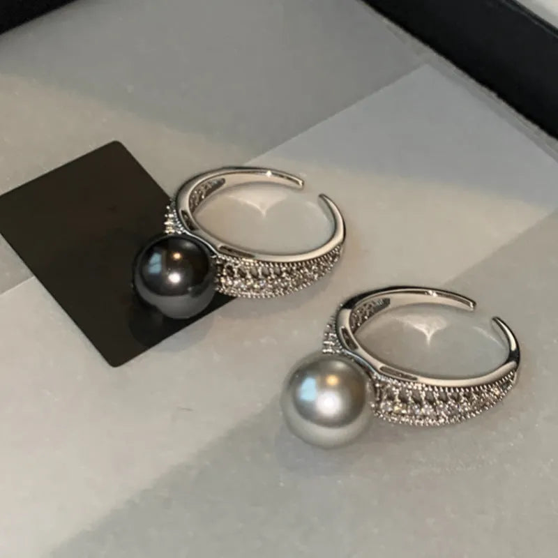 Women's adjustable copper ring with black pearl and geometric open design on an index finger.