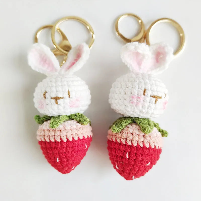 Close-up of a white hand-woven wire rabbit keychain pendant with a strawberry pattern detail.