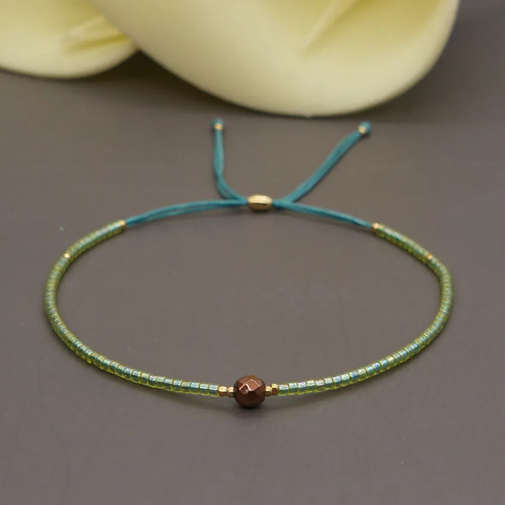 Close-up of a woman's handmade Bohemian bracelet with colourful geometric glass and glaze beads.