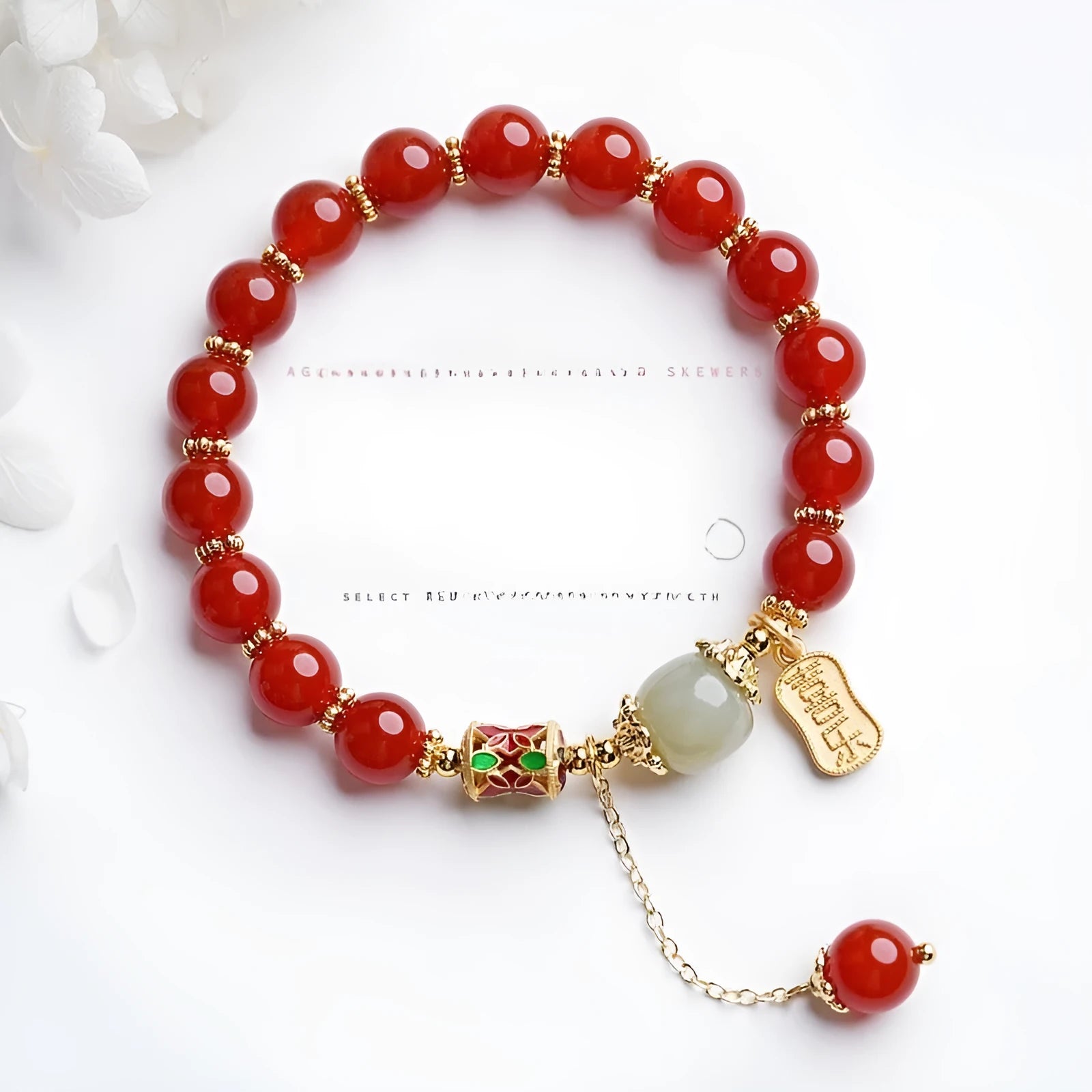 A women's bracelet with red agate beads and gold-plated metal elements on a wrist.