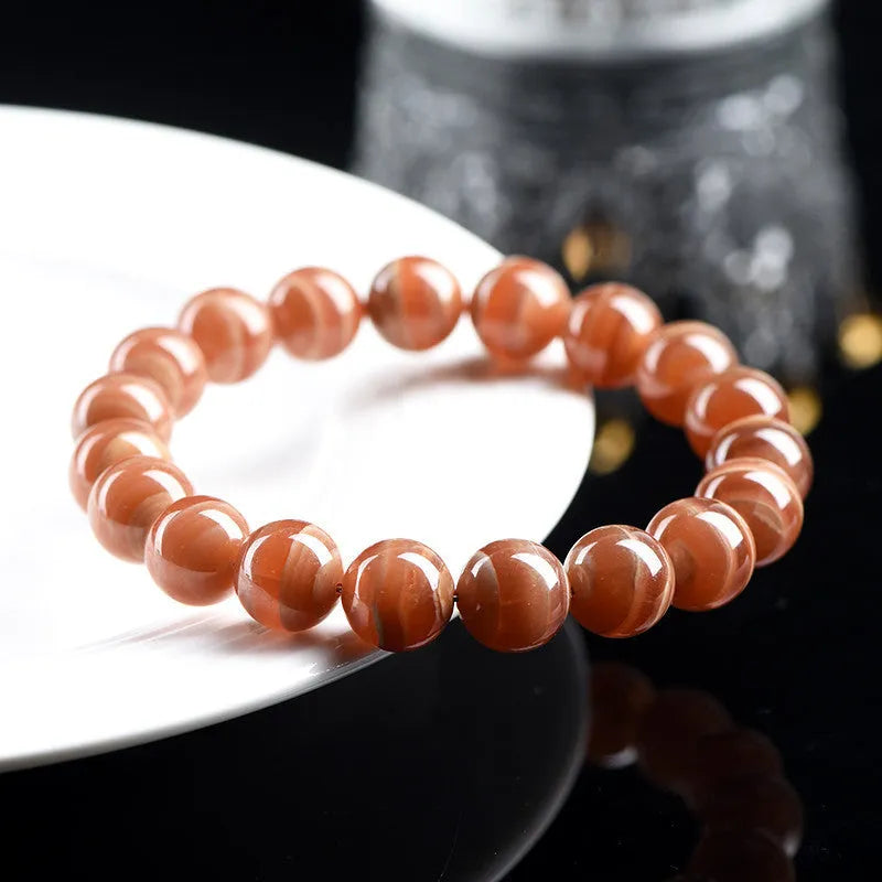 Natural old mine rhodochrosite round bead bracelet with geometric and Ruyi design on a wrist.