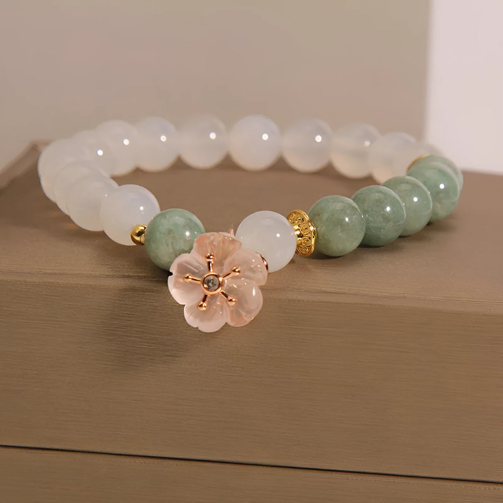 Women's white agate jade flower bracelet on a wrist, showing detailed floral carving.