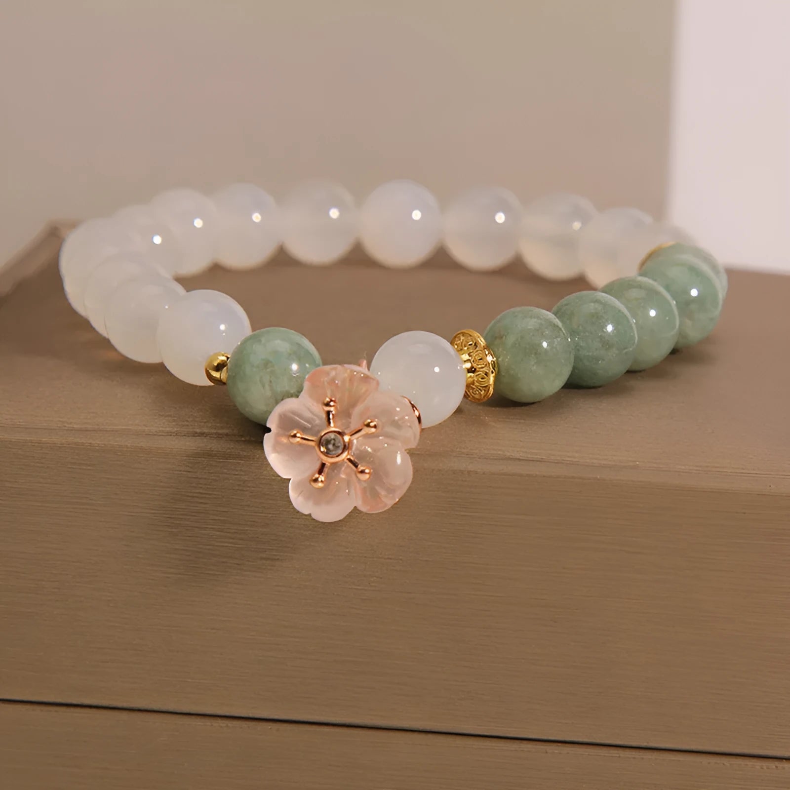 Women's white agate jade flower bracelet on a wrist, showing detailed floral carving.