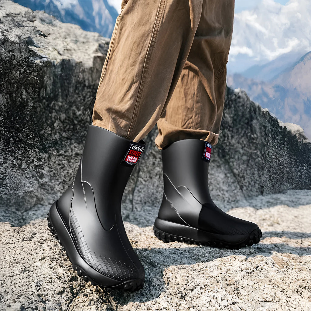 Men's black and red PVC rain boot with a round toe and non-slip plastic sole on a wet surface.