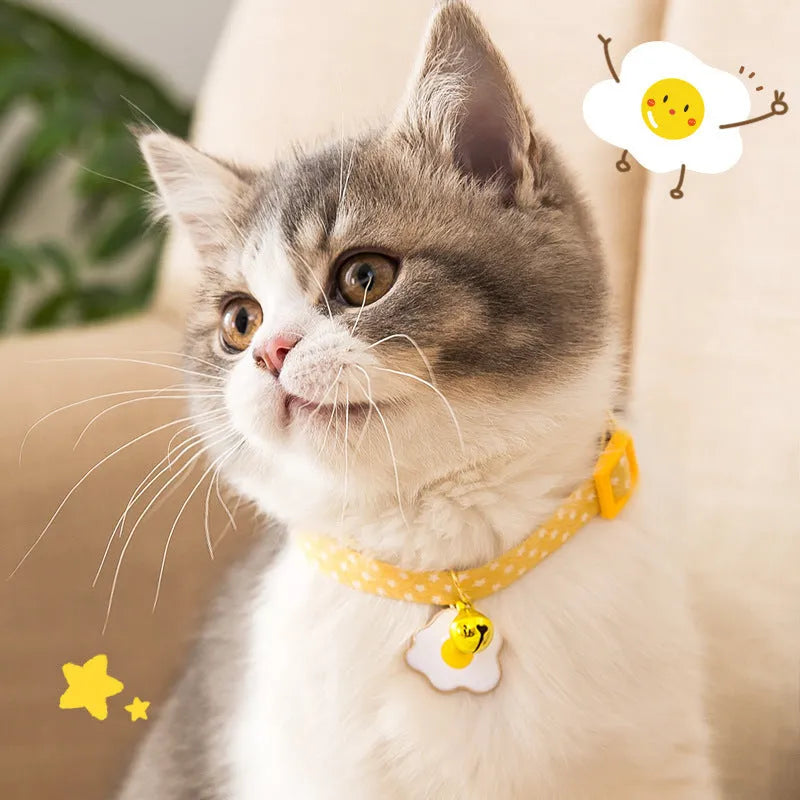 Adjustable green cat collar with a silver bell and pink bow tie on a white background.