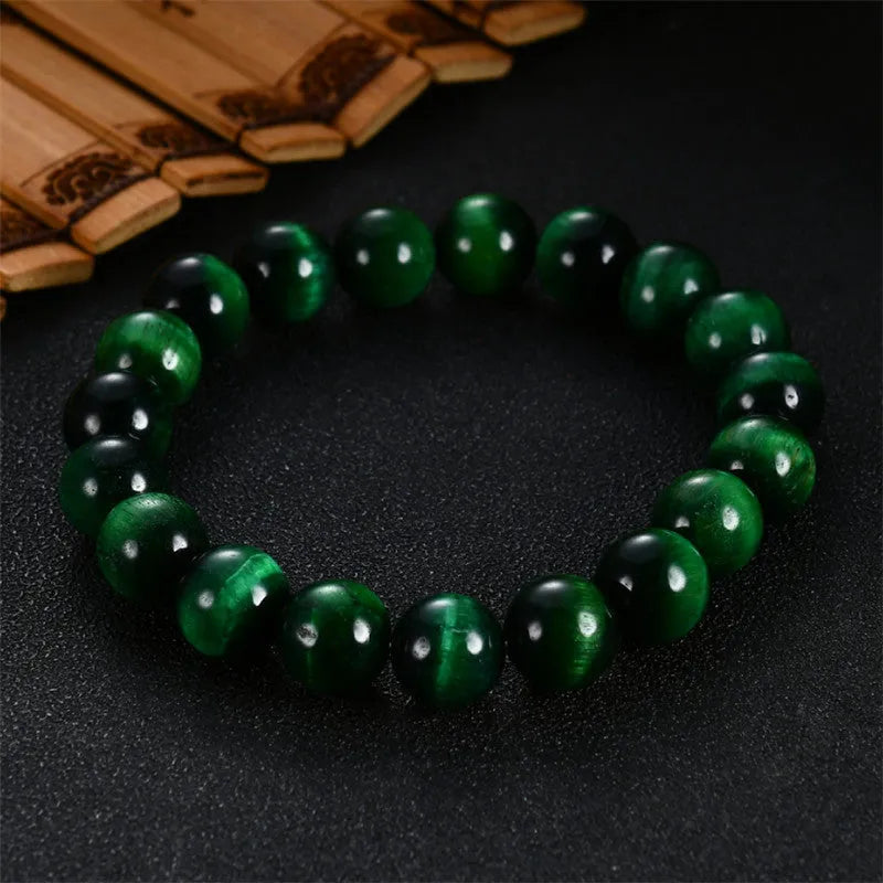 Green tiger eye stone bracelet with geometric shaped beads on a white background.