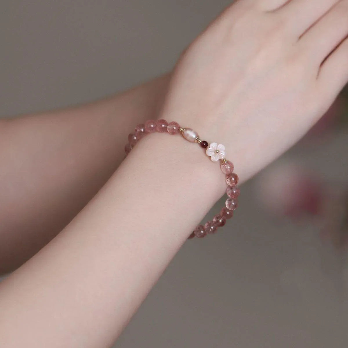 Women's strawberry quartz crystal bracelet with peach blossom flower bead design on wrist