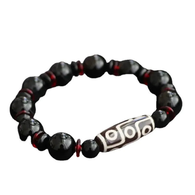 Hand-woven black agate Dzi bead bracelet with chalcedony detail on a wrist.