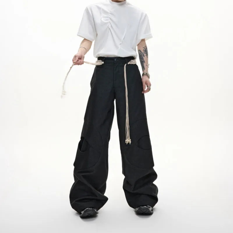 Man's dark blue straight-leg cotton trousers with belt stitching and zipper details on a loose fit.