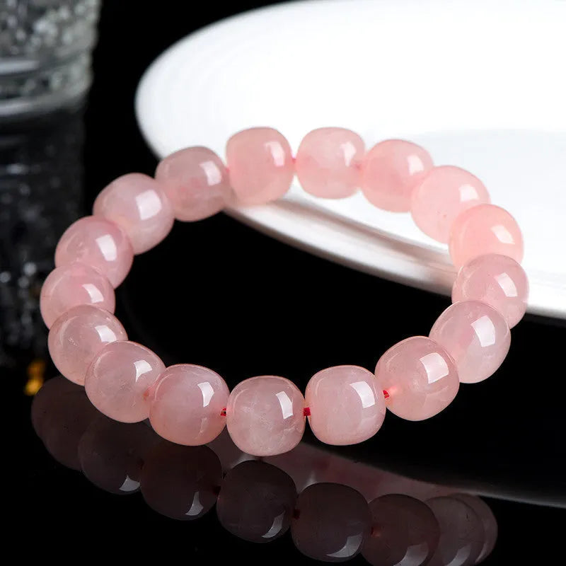 Close-up of a pink natural crystal barrel bead bracelet with geometric beads on a wrist.