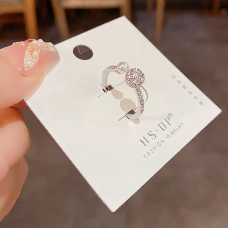 Gold and silver coloured open-end ring with round zircon on a geometric band.