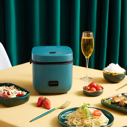 Green 1.2L mini rice cooker with metal body, button controls, and steaming plate on a worktop.