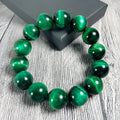 Green tiger eye stone bracelet with geometric shaped beads on a white background.