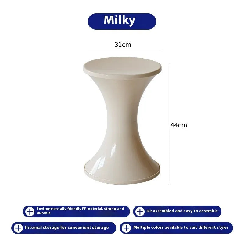 A white hourglass-shaped plastic shoe changing stool on a wooden floor.