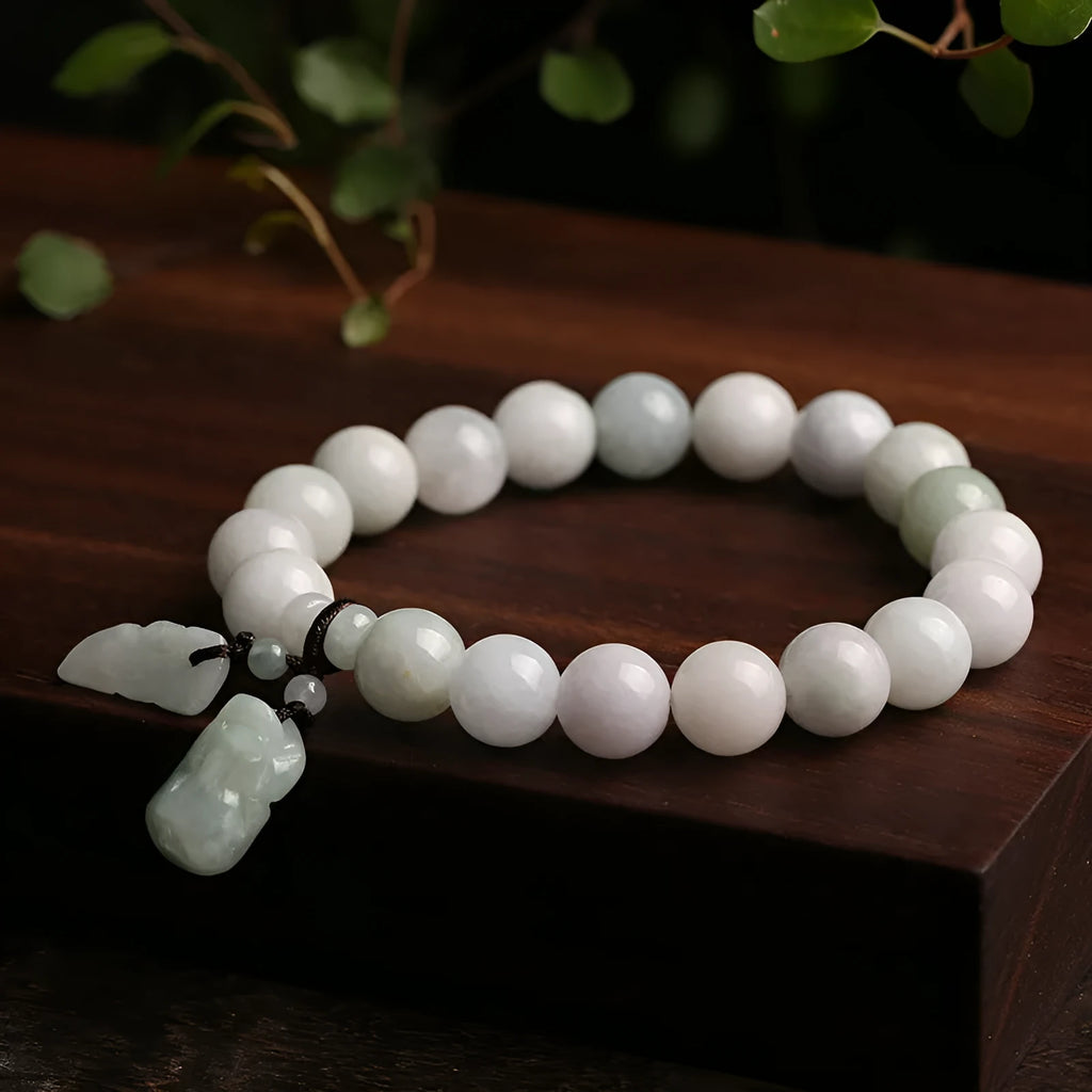 Natural green jade bracelet with a geometric shape and a hanging apple charm on a white background.