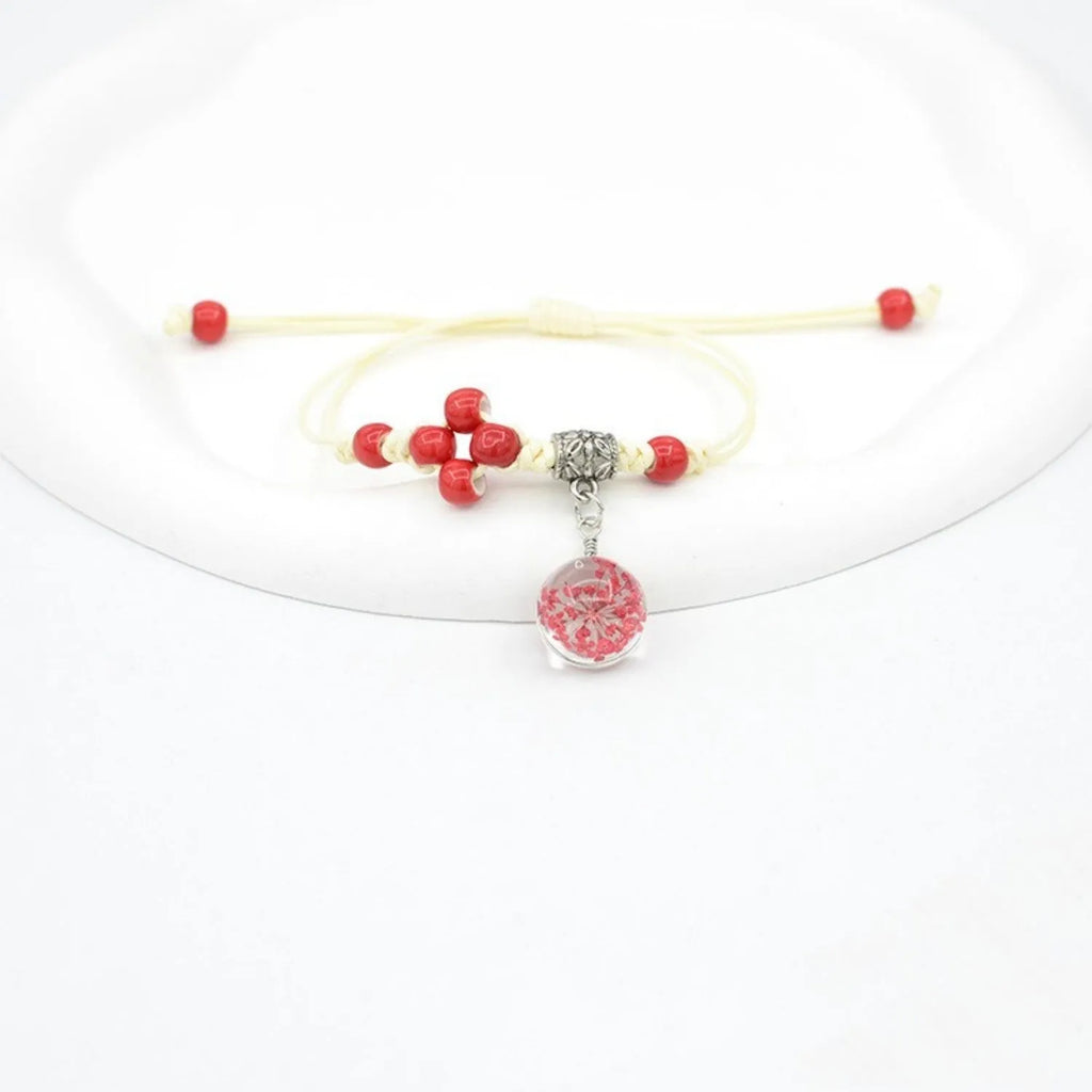 Hand-woven glass bracelet with large beads containing dried flowers and lace decorations, shown in blue.