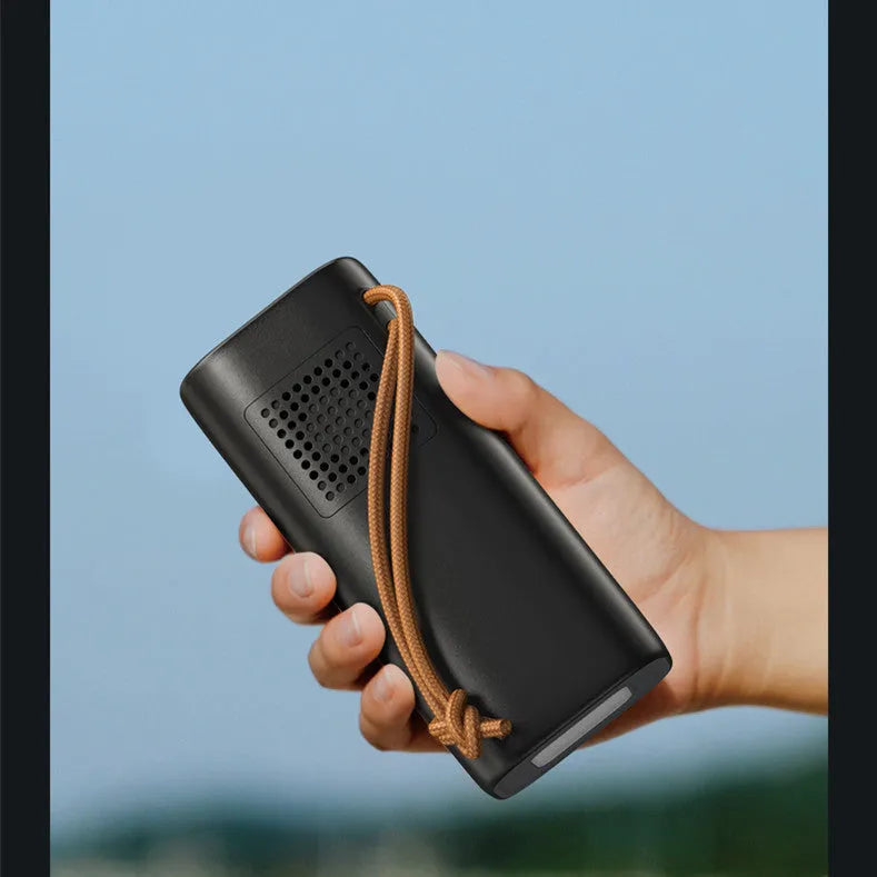 Black portable power bank with solar panel, showing size scale and output ports.