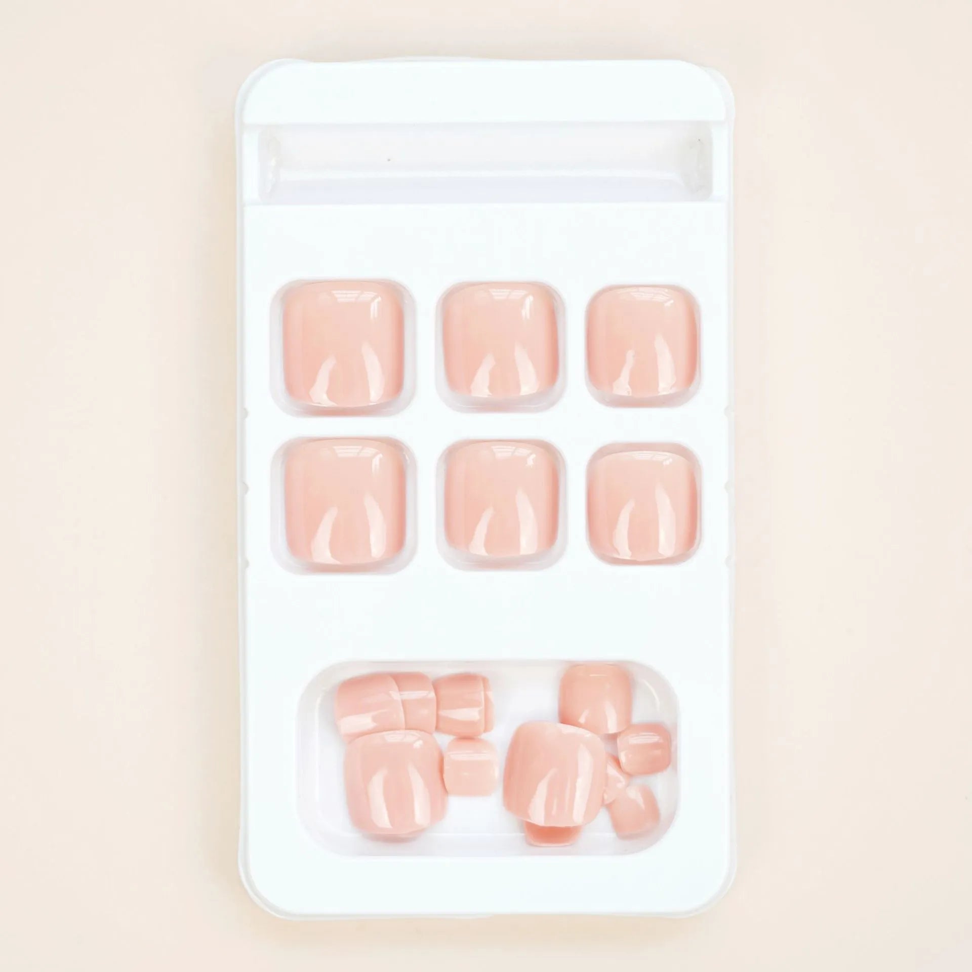 Finished plastic toe nail stickers in J-52 skin colour with glue tube on white background.