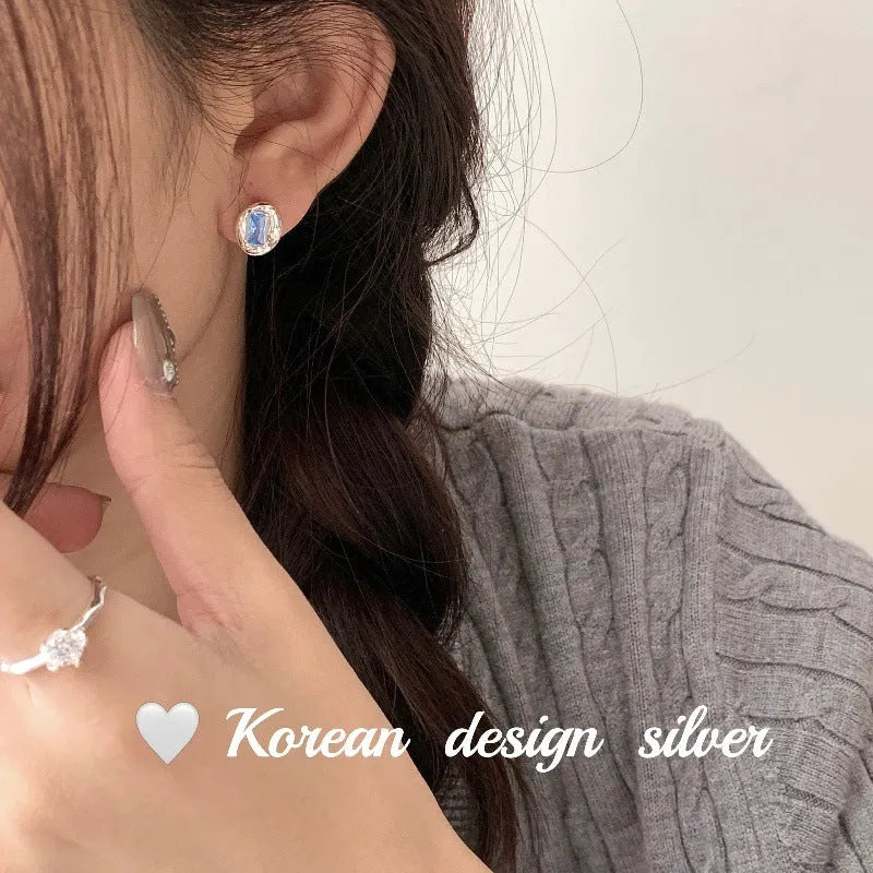 Sterling silver earrings with heart-wrapped oval blue diamond design and electroplated finish