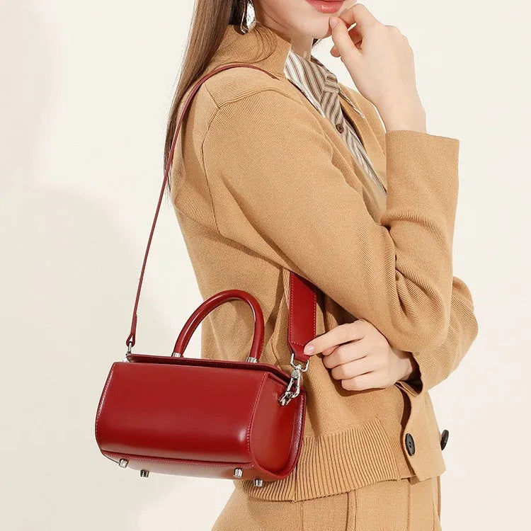Brown leather women's crossbody bag with a box shape and clamshell opening, shown with interior phone and file pockets.