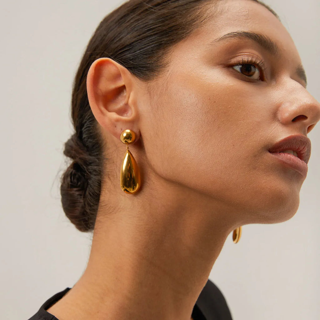 Gold coloured stainless steel earrings with a geometric hemisphere and water drop pendant design.