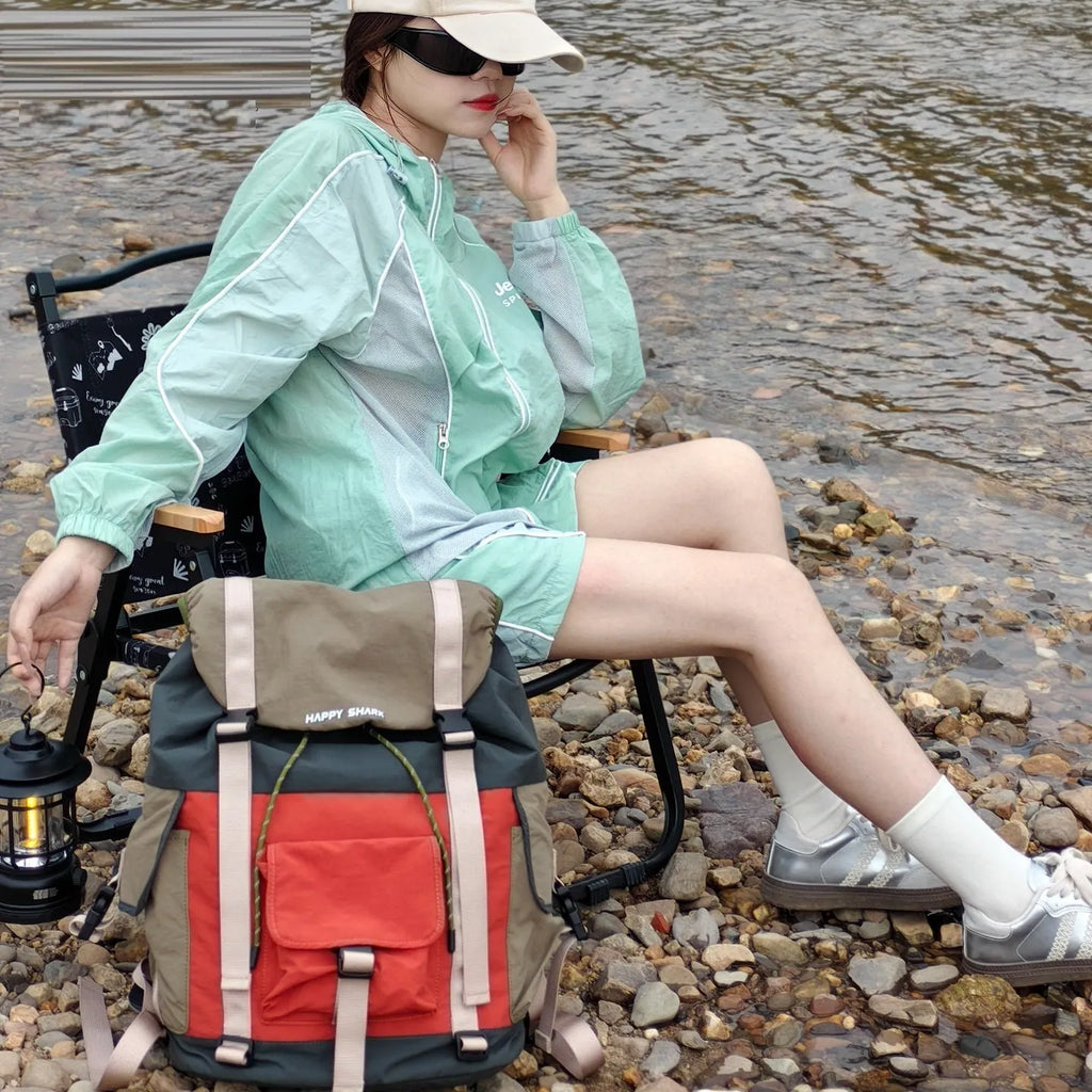 Orange and green contrast colour outdoor backpack with multiple compartments, shown from the side.