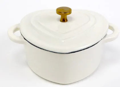 Heart-shaped cast iron enamel stew pot in Milk White with lid on a stovetop