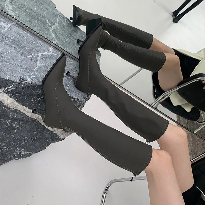 Women's black pointed toe below knee stiletto heel boots with a back zipper on display.